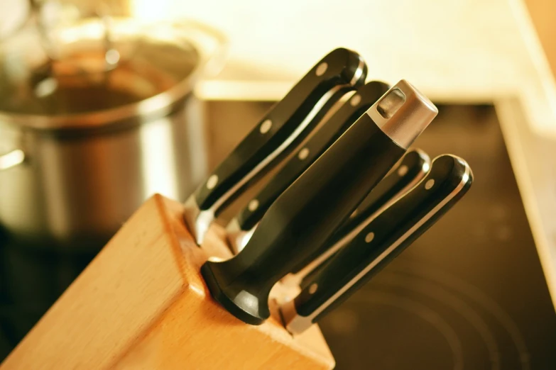 a group of knives sitting on top of a wooden block, a picture, shutterstock, stove, low-angle shot, rack focus, portlet photo