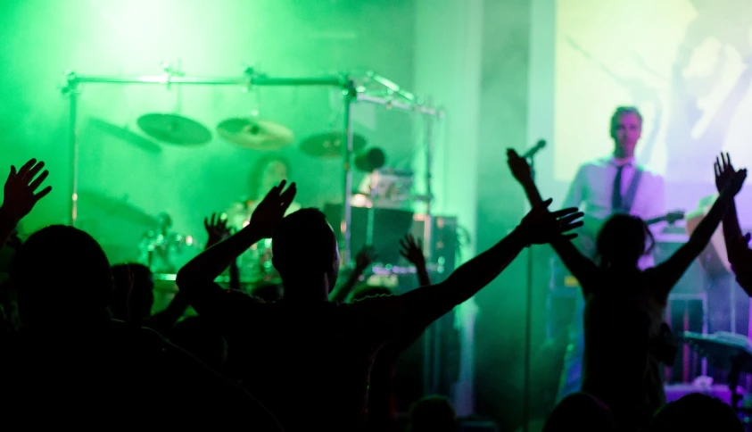 a group of people that are standing in front of a stage, a picture, by Matt Cavotta, pexels, ambient green light, music being played, scene from church, arms held high in triumph