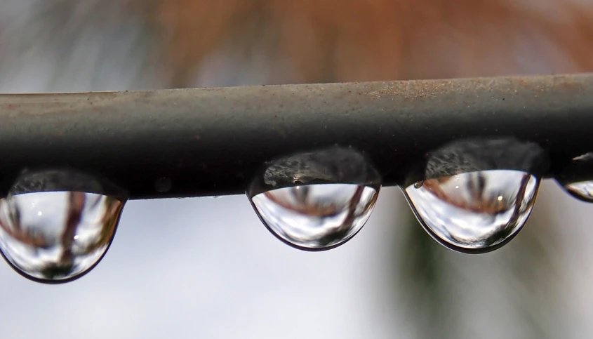 a group of water droplets sitting on top of a metal bar, connected trough wired, photo 85mm, tear drop, two