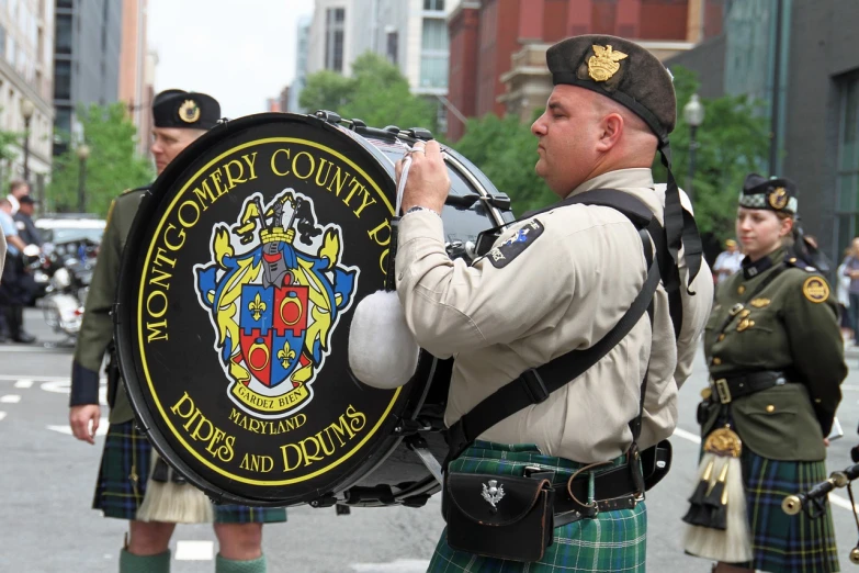 a man in a kilt playing a drum, a photo, by Scott M. Fischer, shutterstock, hybrid of pig and nyc policeman, cannon mounted on back, pittsburgh, family crest