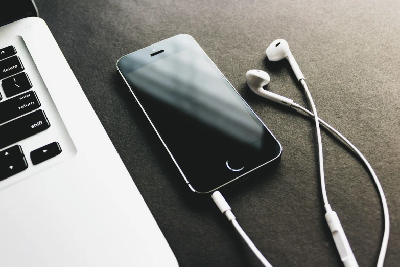 a cell phone sitting next to a laptop computer, a picture, trending on pexels, earphones, charcoal and silver color scheme, shot on an iphone, detailed product photo