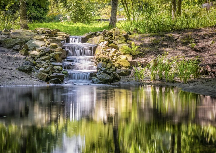 a small waterfall flowing through a lush green forest, a picture, inspired by Ethel Schwabacher, pixabay, reflective water koi pond, slow exposure hdr 8 k, sunny day time, terraced orchards and ponds