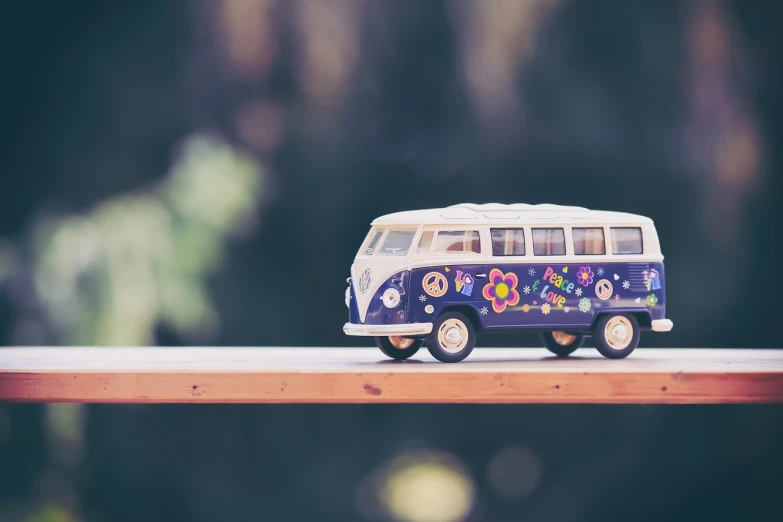 a toy van sitting on top of a wooden table, unsplash, hippie motifs, purple themed, close-up photo, wide shot photo