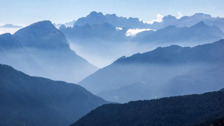 a view of the mountains from the top of a mountain, a picture, by Sebastian Spreng, telephoto photography, alessandro barbucci, valley mist, indigo