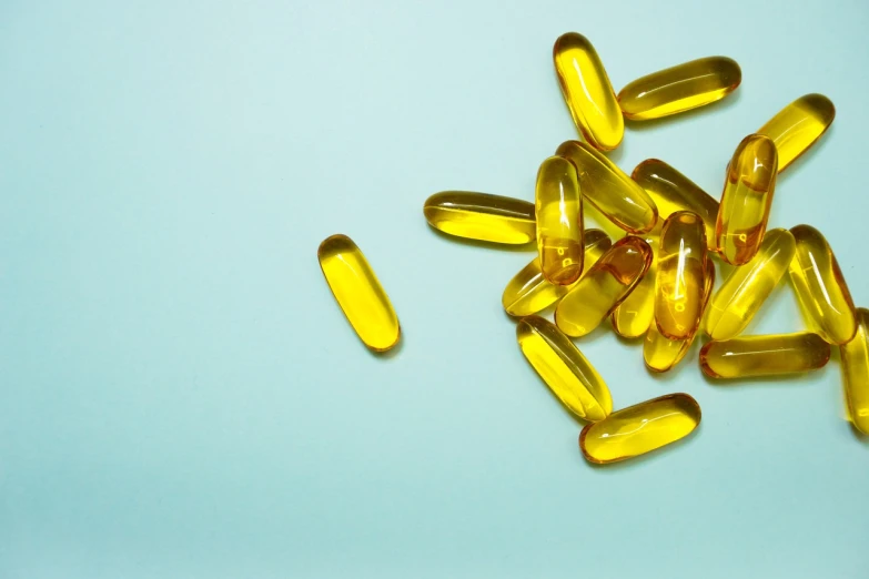 a pile of yellow pills sitting on top of a blue surface, renaissance, olive oil, fish, header, full body image