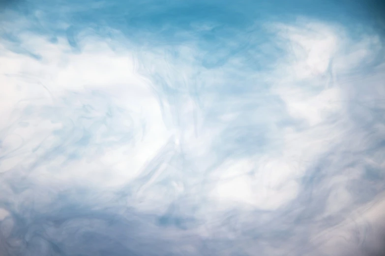 a plane flying through a cloudy blue sky, a picture, inspired by Anna Füssli, conceptual art, ground mist swirling vortexes, vertical wallpaper, white cyclops portrait in sky, swirling wispy smoke