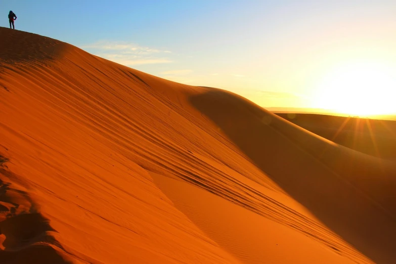 a person standing on top of a sand dune, by Etienne Delessert, hurufiyya, epic red - orange sunlight, photo of a beautiful, moroccan, 4k serene