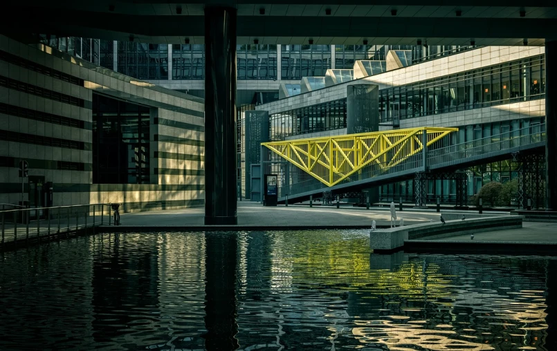 a yellow bridge over a body of water, by Raphaël Collin, flickr, modernism, brutalist courtyard, 8k 50mm iso 10, morphosis, dynamic!!