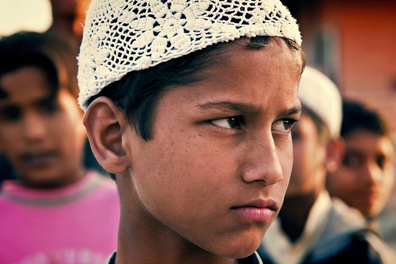 a close up of a person wearing a hat, flickr, hurufiyya, 14 yo berber boy, on an indian street, wearing a pink head band, looking serious