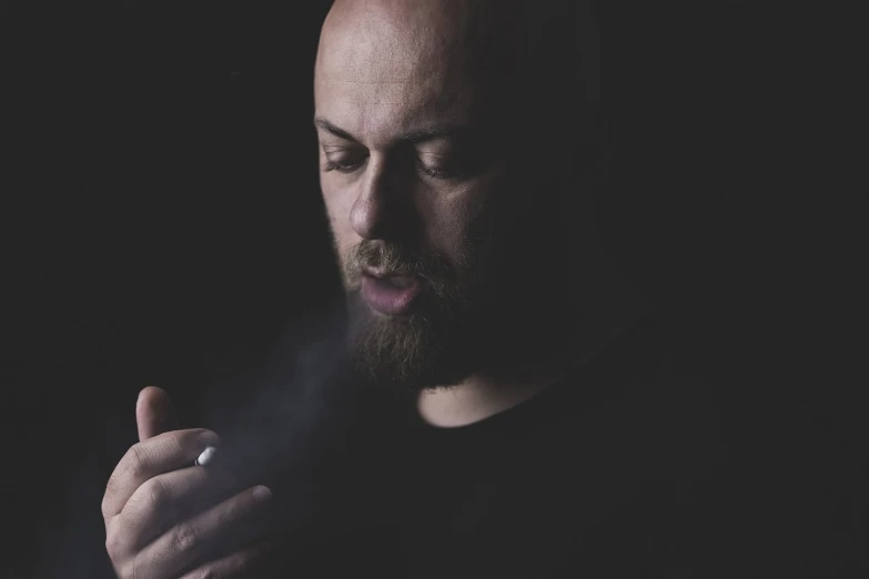 a man with a beard smoking a cigarette, inspired by Hallsteinn Sigurðsson, pexels, portrait of bald, vantablack cloth technology, volumetric haze, his palms are sweaty