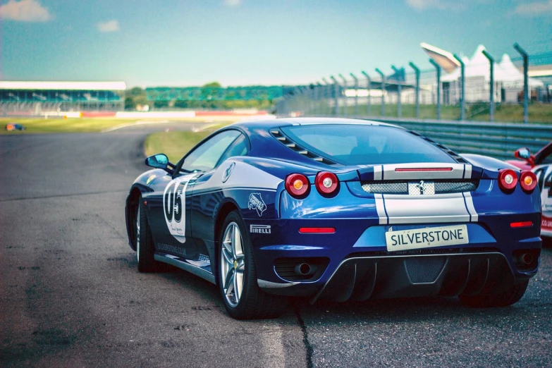 a blue sports car driving down a race track, shutterstock, beautiful wallpaper, ferrari, backview, blue silver and black