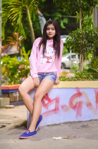 a beautiful young woman sitting on top of a cement wall, a picture, by Cherryl Fountain, wearing a pink hoodie, kuntilanak on tree, sexy girl wearing shorts, young cute wan asian face