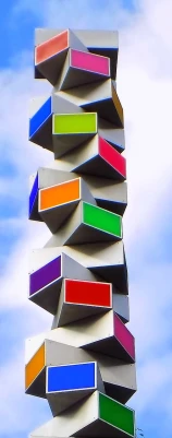 a tall tower of multicolored books against a blue sky, an abstract sculpture, inspired by Jodorowsky, flickr, modular constructivism, bright signage, hexagons, 1 9 7 2, desaturated colours
