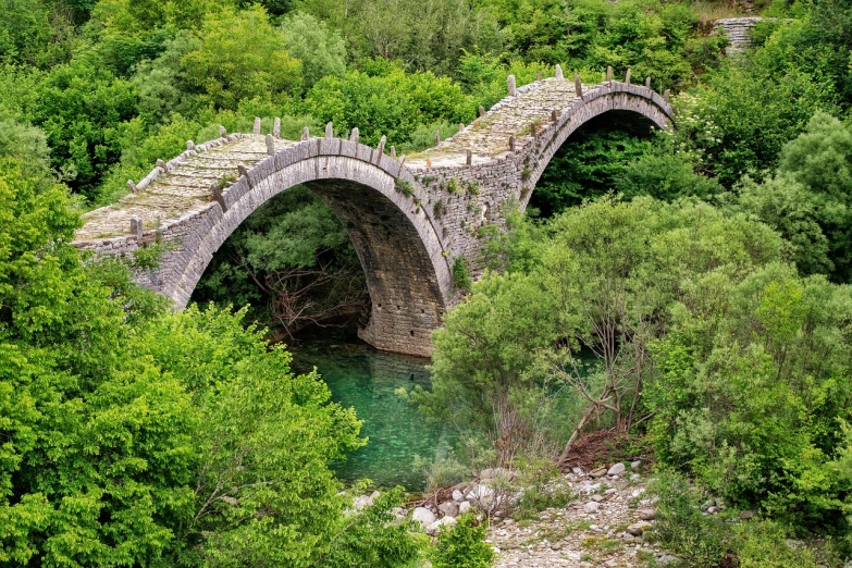 a stone bridge over a river surrounded by trees, a picture, by Sava Šumanović, shutterstock, greece, suspended bridge!, very very well detailed image, green waters