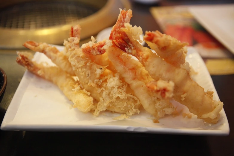 a close up of a plate of food on a table, a picture, sōsaku hanga, long spider paws, very crispy, side profile view, battered