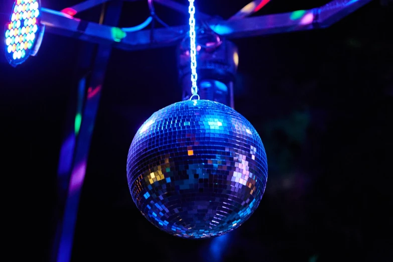 a disco ball hanging from a string in a dark room, shutterstock, taken in night club, purple and blue colored, 7 0 s photo