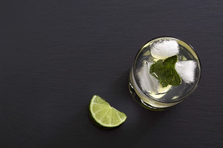 a glass filled with ice and a slice of lime, pexels, photorealism, mint leaves, view from above, on a black background, product introduction photo