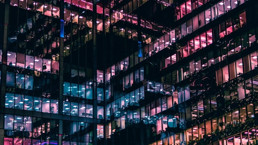 a building with many windows lit up at night, a screenshot, by Sebastian Spreng, pexels contest winner, modernism, hq 4k phone wallpaper, layers of colorful reflections, office cubicle background, pink reflections