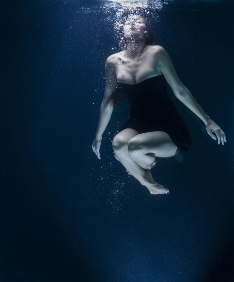a woman in a swim suit dives under water, a portrait, art photography, falling, dark blue water, wearing a dress made of water, low angle photo