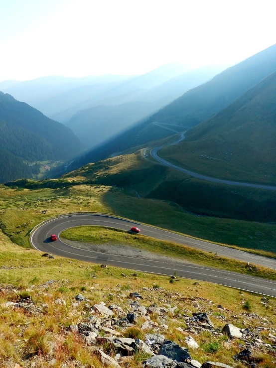 a car driving down a winding mountain road, a photo, romanian, sweeping vista, hot summer sun, devils horns