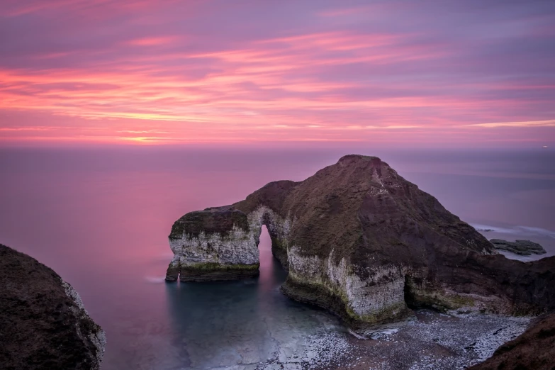 a rock formation in the middle of a body of water, a picture, by Andrew Geddes, romanticism, pink arches, yorkshire, sunrise coloring the room, benjamin vnuk