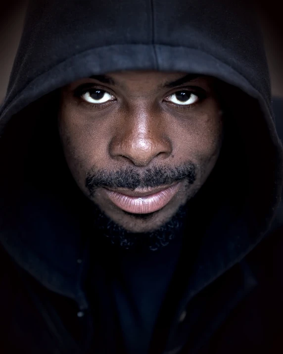 a close up of a person wearing a hoodie, a character portrait, by Etienne Delessert, african man, headshot photo, mc ride, hard lighting!