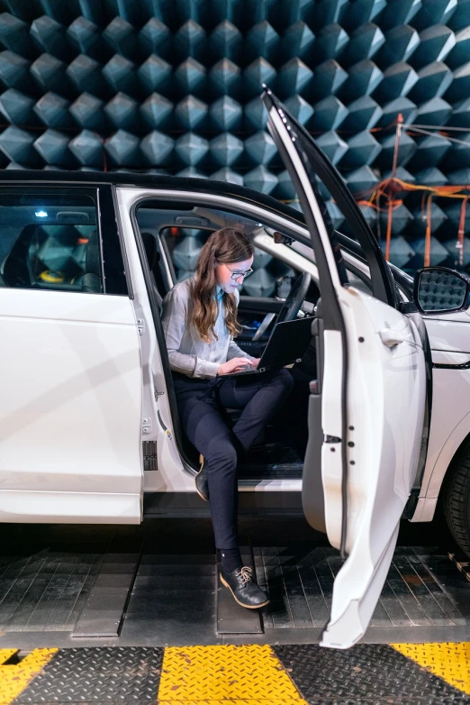 a woman sitting in the driver's seat of a white car, by Emma Andijewska, testing custom, aura jared and wires, discovered for the first time, full height