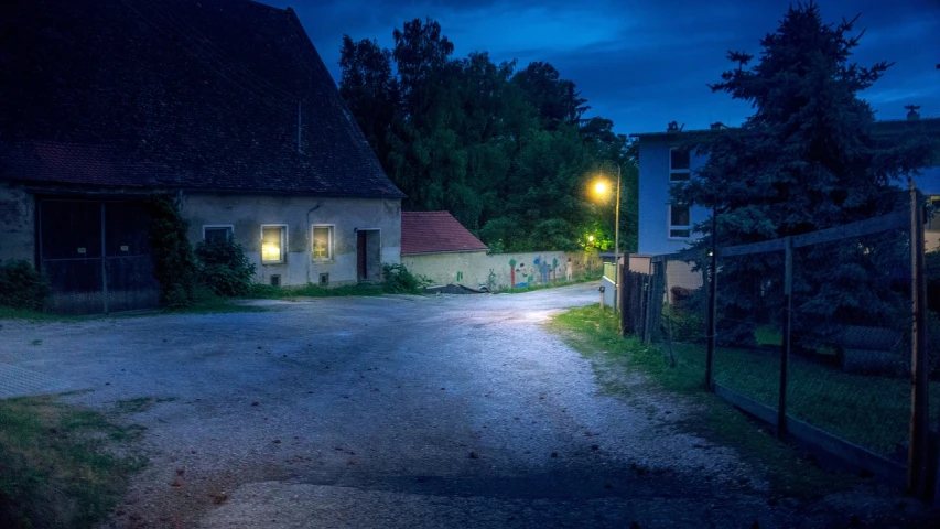 a street with a light at the end of it, a picture, by Karl Hagedorn, shutterstock, nightime village background, in the countryside, f / 1. 9 6. 8 1 mm iso 4 0, blue night