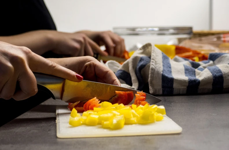 a person cutting vegetables on a cutting board, a stock photo, process art, close together, red-yellow colors, dark kitchen of an art student, frying nails