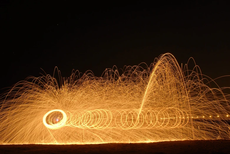 a long exposure photograph of a fire spinning in the air, a stipple, flickr, shock art, sand swirling, photo taken at night, detailed wide shot, machine gun fire