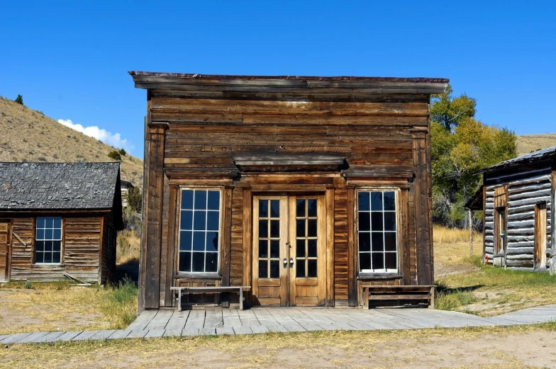 a small wooden building sitting in the middle of a field, a portrait, renaissance, wild west background, storefront, usa-sep 20, tall obsidian architecture