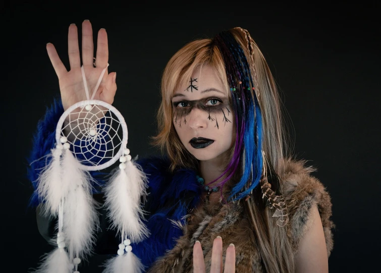 a woman with makeup and feathers holding a dream catcher, a character portrait, inspired by Chica Macnab, gothic art, blue glass dreadlocks, anime girl cosplay, photo of a hand jewellery model, 2045