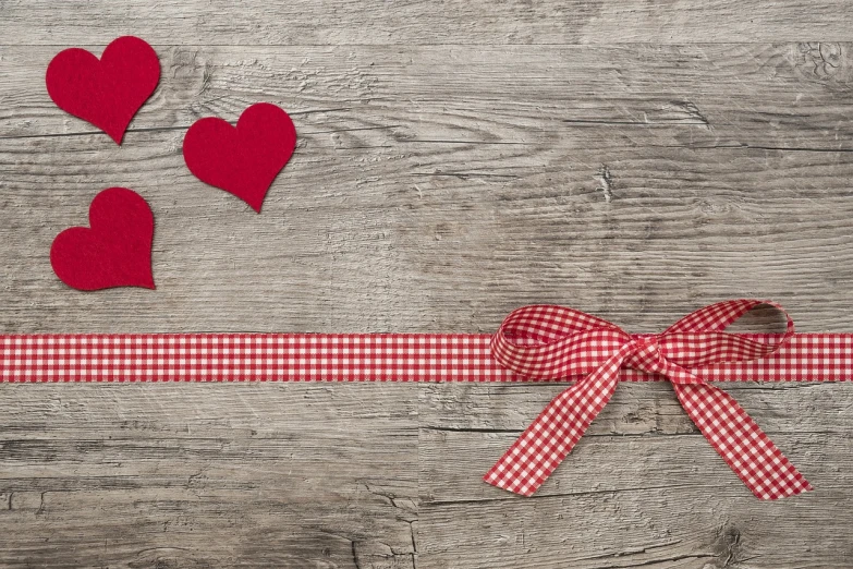 a red and white checkered ribbon and hearts on a wooden background, pixabay, 🎀 🗡 🍓 🧚, cover shot, bow, wide wide shot