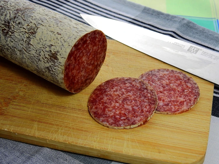 a sliced sausage on a cutting board next to a knife, a portrait, pixabay, mingei, pepperoni, smooth oval head, bark, looking towards camera