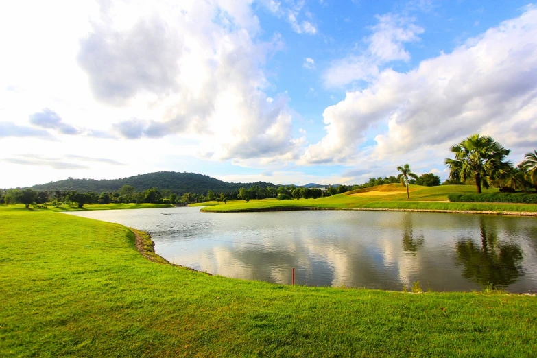 a body of water sitting on top of a lush green field, by Bernardino Mei, sumatraism, golf course, dlsr photo, very beautiful photo, enhanced photo