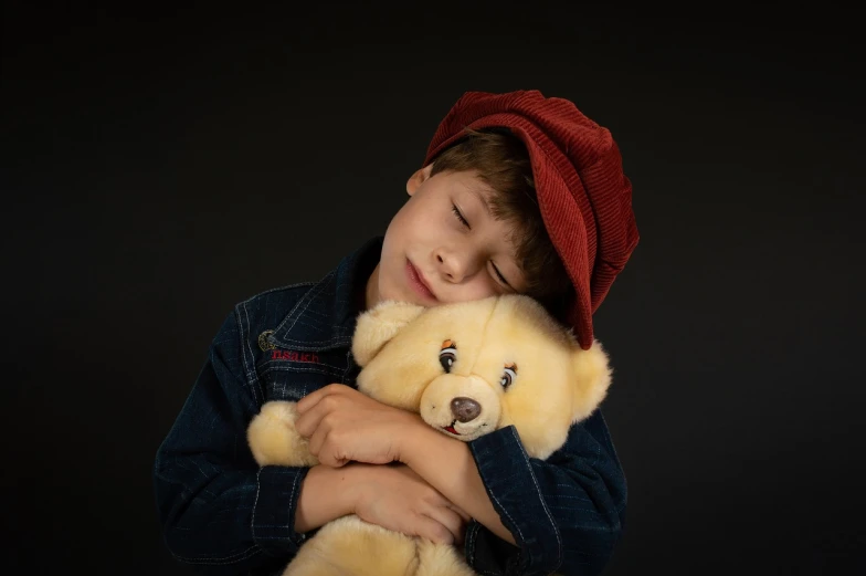 a young boy is holding a teddy bear, a stock photo, sleepy feeling, he is wearing a hat, shot at dark with studio lights, hugging each other