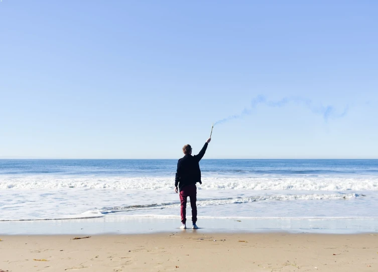 a person standing on a beach flying a kite, inspired by Storm Thorgerson, conceptual art, smoke grenades, holding a paintbrush in his hand, usa-sep 20, single long stick