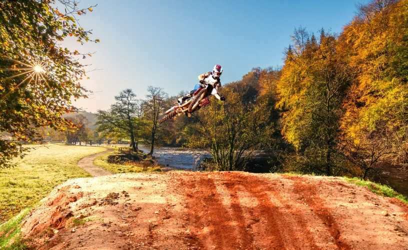 a man flying through the air while riding a dirt bike, a picture, by Julian Allen, shutterstock, autumnal, ultra wide shot, part dean cornwell style, 4k photo