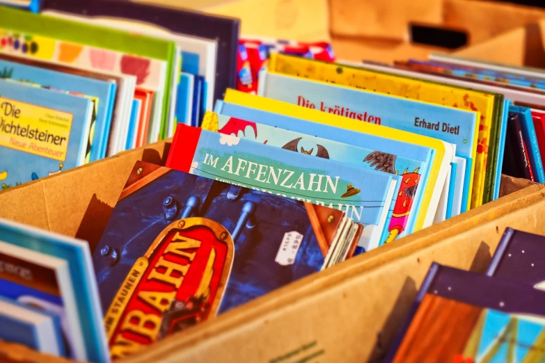 a box filled with books sitting on top of a table, a storybook illustration, by Armin Baumgarten, shutterstock, blurred detail, vienna, comic books, stock photo