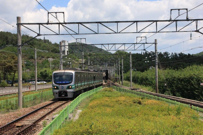 a train traveling down train tracks next to a lush green hillside, by Sengai, flickr, sōsaku hanga, underground metro, gwanghwamun, 2 0 2 2 photo, 7 7 7 7
