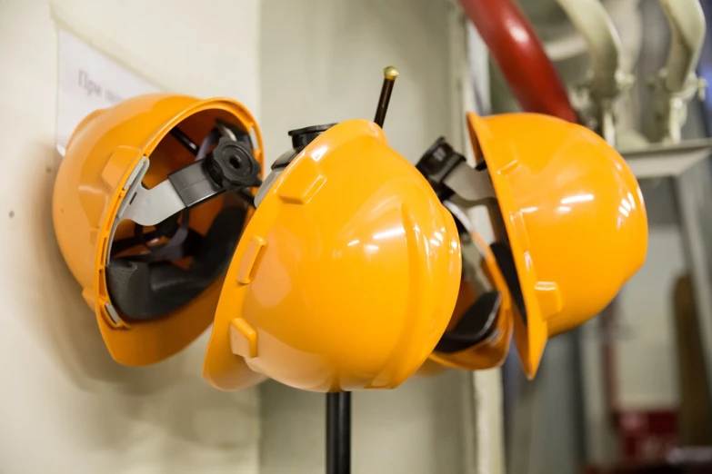 a bunch of hard hats hanging on a wall, a picture, by Lee Loughridge, shutterstock, orange safety labels, turbines, close up details, closed visor