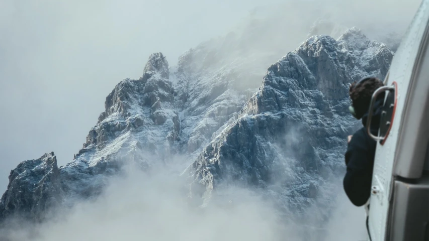 a view of a mountain through the window of a plane, a matte painting, by Matthias Weischer, pexels contest winner, romanticism, in the thick fog, in the dolomites, telephoto shot, rugged face