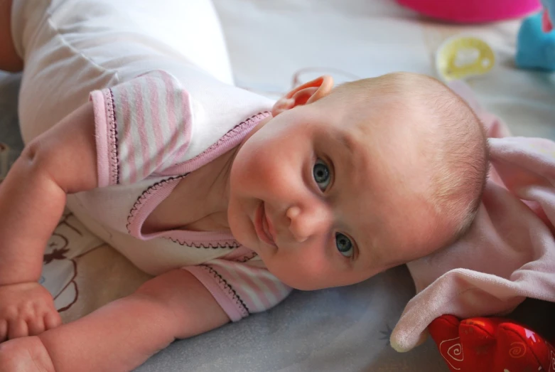 a close up of a baby laying on a bed, flickr, softplay, gentle smile, bunny, anna nikonova