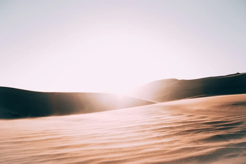 a person riding a snowboard down a snow covered slope, a picture, trending on pexels, light and space, deep golden sand desert, hazy light rays, new mexican desert background, landscape of flat wastelands