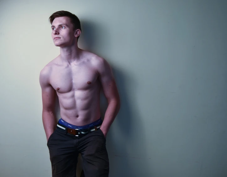 a shirtless man leaning against a wall, a portrait, inspired by Harry Morley, flickr, grim fashion model looking up, smooth pale skin, bare midriff, 155 cm tall