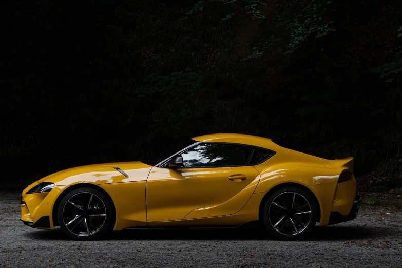 a yellow sports car parked in a parking lot, a picture, inspired by Kanō Shōsenin, unsplash contest winner, synthetism, toyota supra, with a black dark background, soft light from the side, portrait n - 9