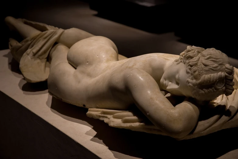 a statue that is laying down on a table, a marble sculpture, by Antonio Canova, flickr, beautiful curves, sfw version, lit from the side, onyx