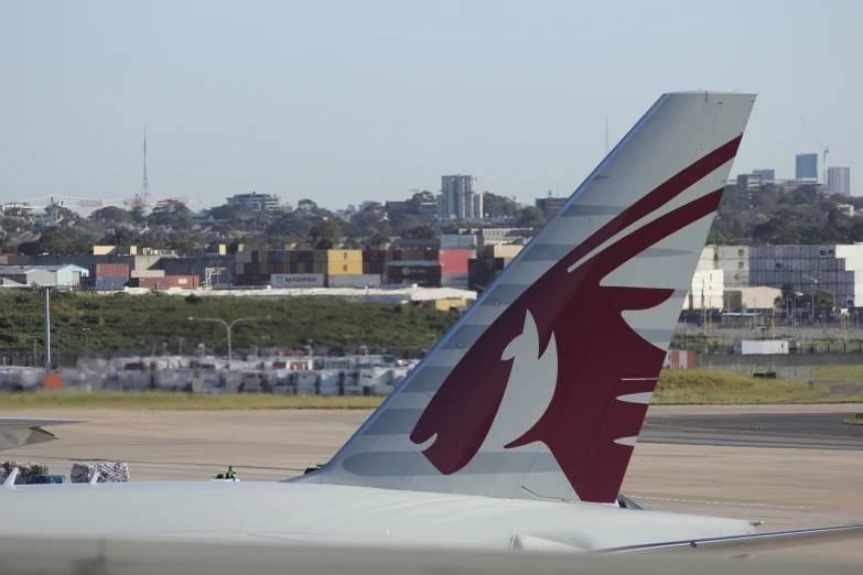 a large jetliner sitting on top of an airport tarmac, a picture, by Matt Stewart, flickr, hurufiyya, maroon and white, sydney, seen from a distance, tail fin