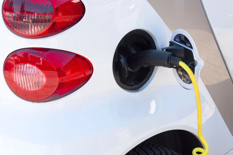 a close up of a white car with a yellow hose attached to it, shutterstock, electric energy, rear lighting, round-cropped, plasma charges