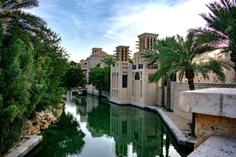 a river running through a lush green forest filled with trees, inspired by Ricardo Bofill, hurufiyya, arabic architecture, las vegas, waterfront houses, with palm trees in the back